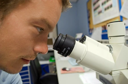 Closeup of man looking into microscope.