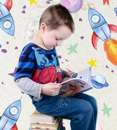 Young boy reading a book with background of drawn rockets, stars, and planets.