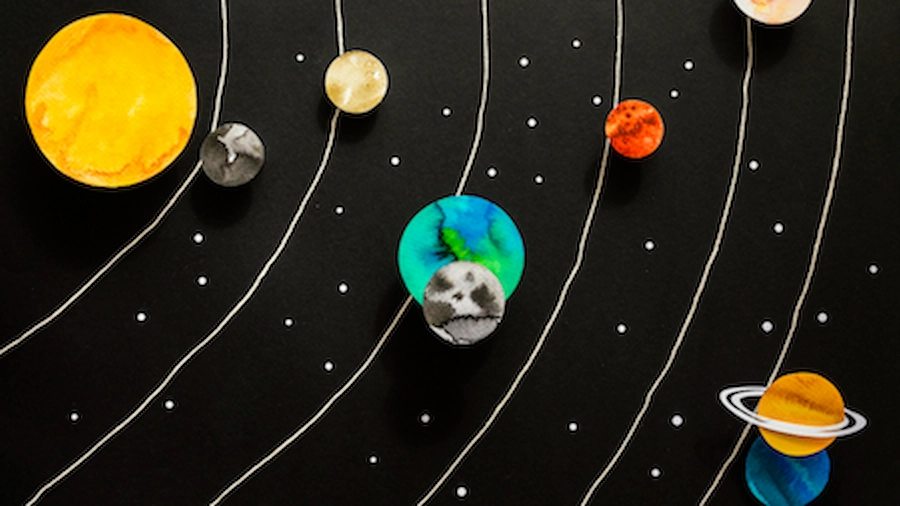 Paper-cutout solar system with the sun, planets, and Earth's moon nearby.